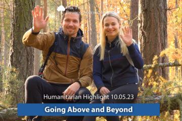 A male and female couple waving and smiling in a beyond forest.